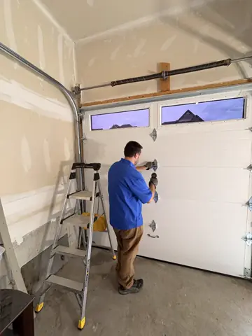Technician installing hardware on a white garage door